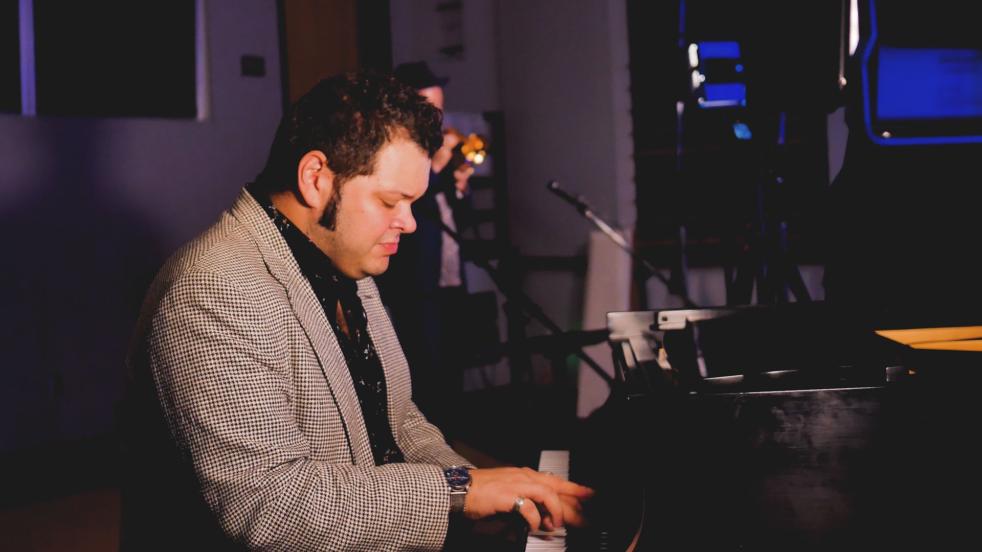 A man with a beard is playing a saxophone in a dark room.