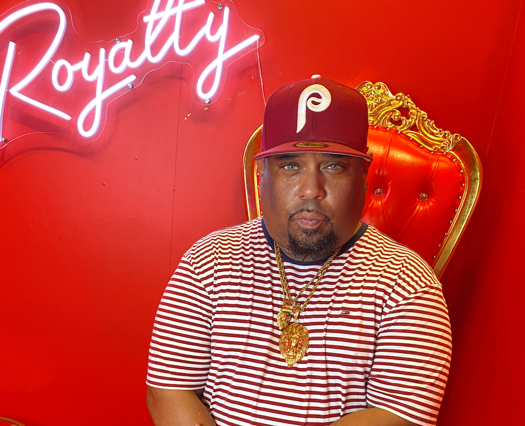 a man sitting in front of a sign that says royalty