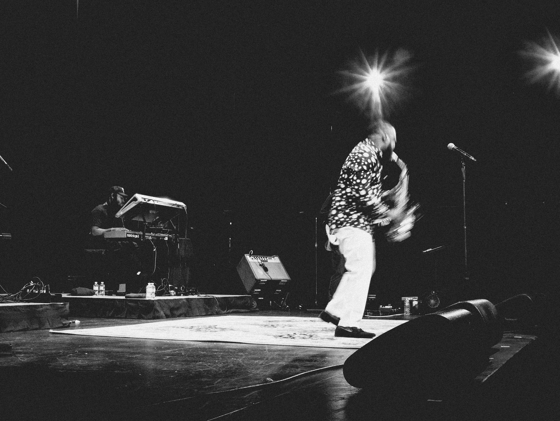 A black and white photo of a man playing a saxophone on a stage