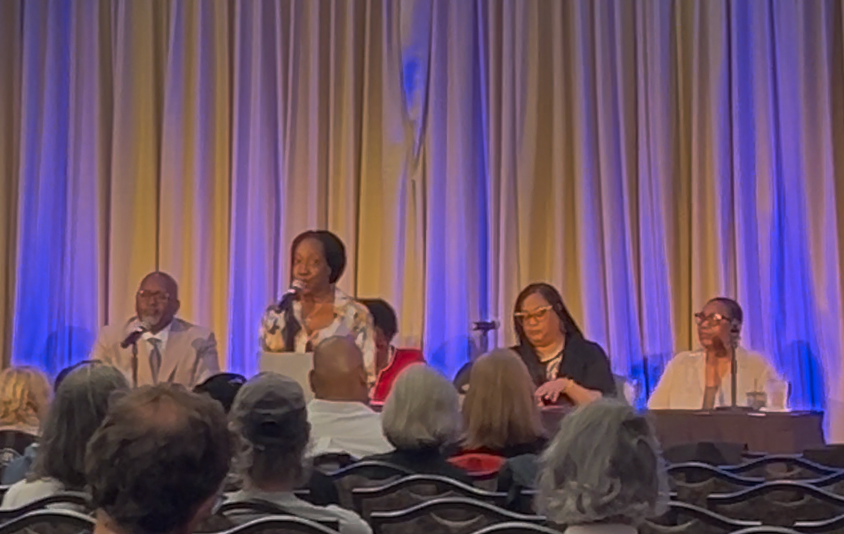 A group of people are sitting at a table talking into microphones.