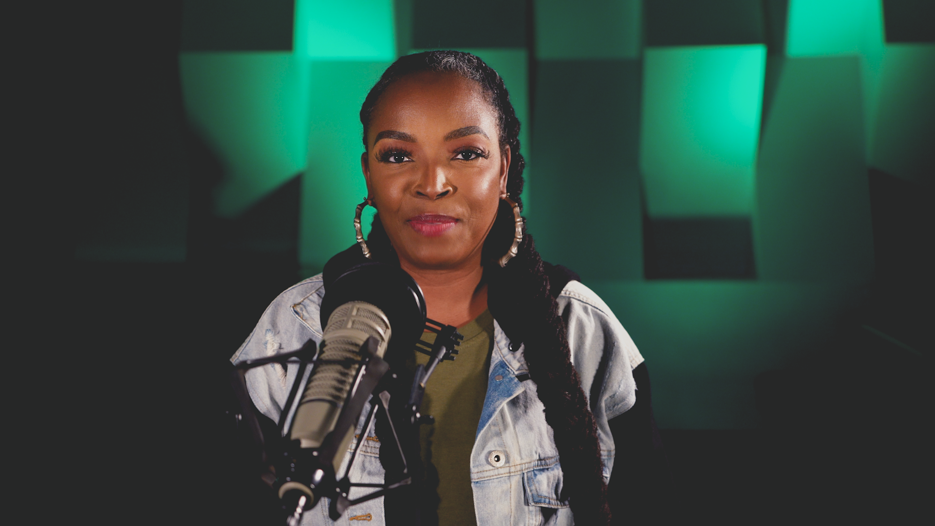 A woman is standing in front of a microphone in a recording studio.