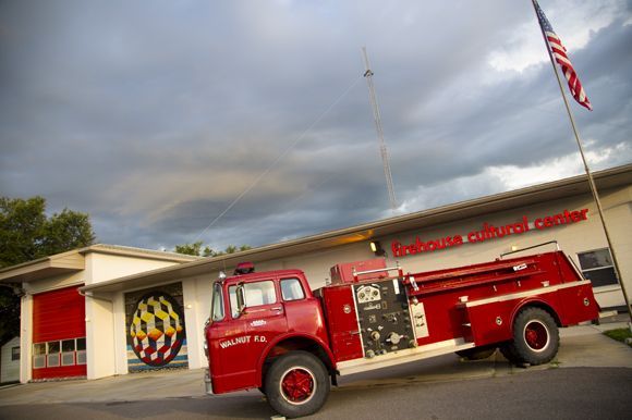 A red fire truck is parked in front of a fire station.