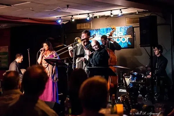 a group of people are playing instruments on a stage in front of a tama drum set .