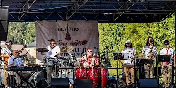 a group of men are standing on a stage playing instruments .