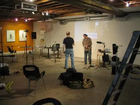 two men are standing in a room with a projector screen .