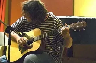 a man is playing an acoustic guitar in front of a microphone .