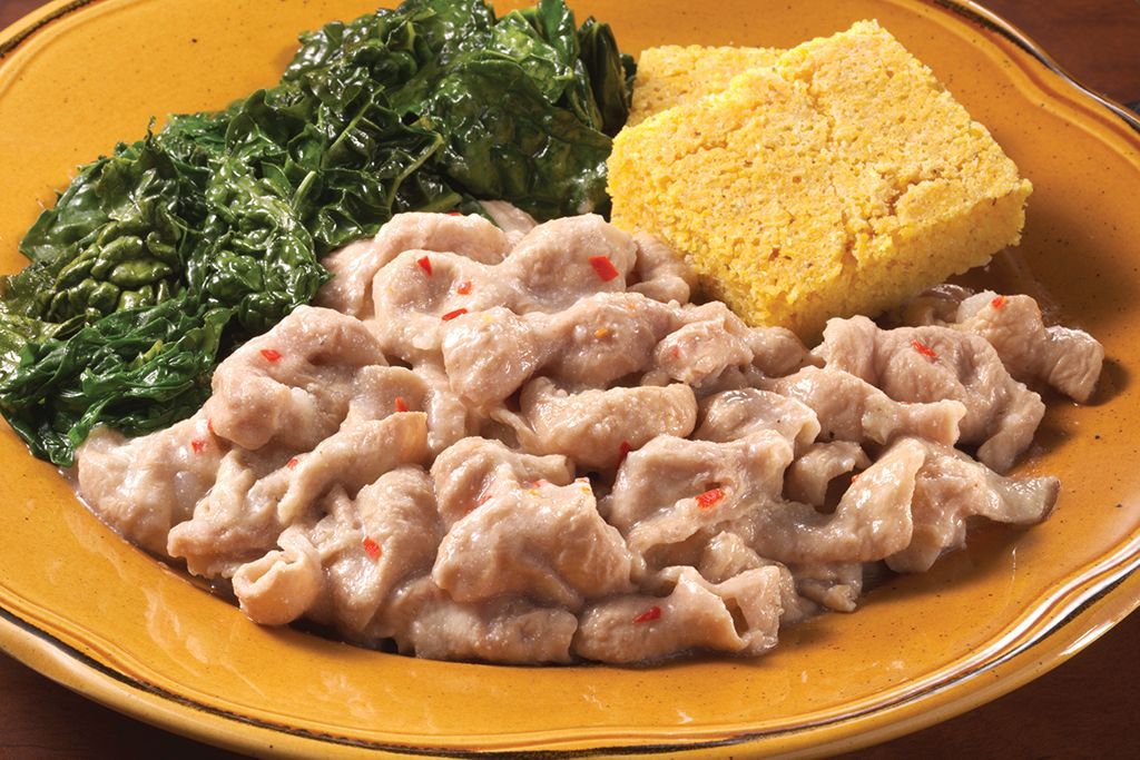 A close up of a plate of food with spinach and cornbread