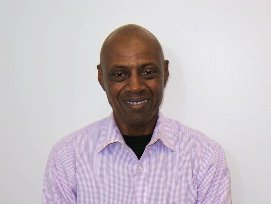 A man in a purple shirt is smiling for the camera.