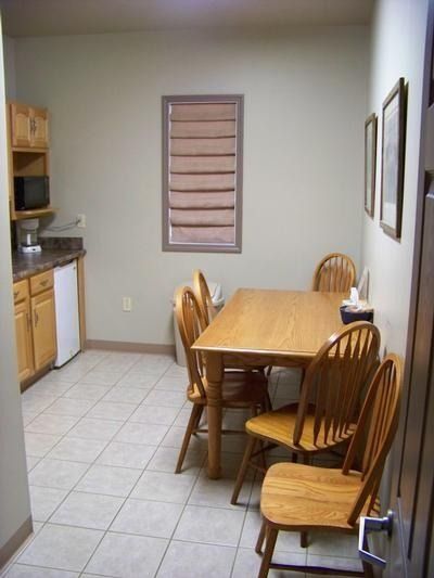 Small kitchen with wooden dining table and chairs, tiled floor, and cabinets along the left wall.