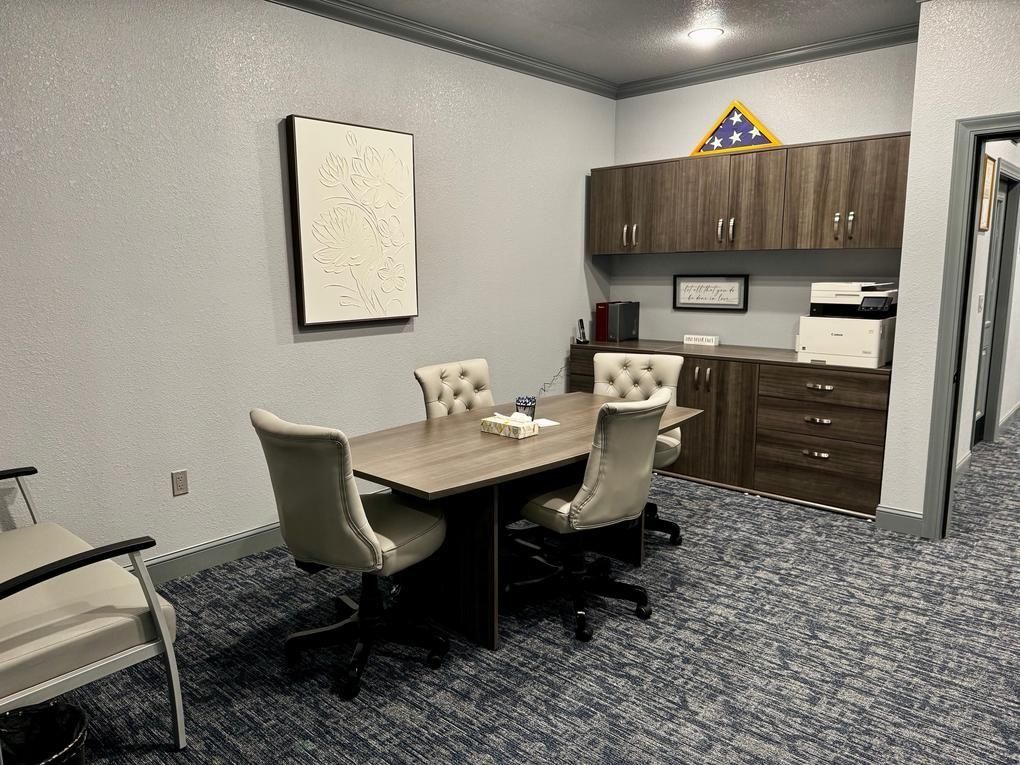 Small conference room with table, chairs, cabinets, and patterned carpet.