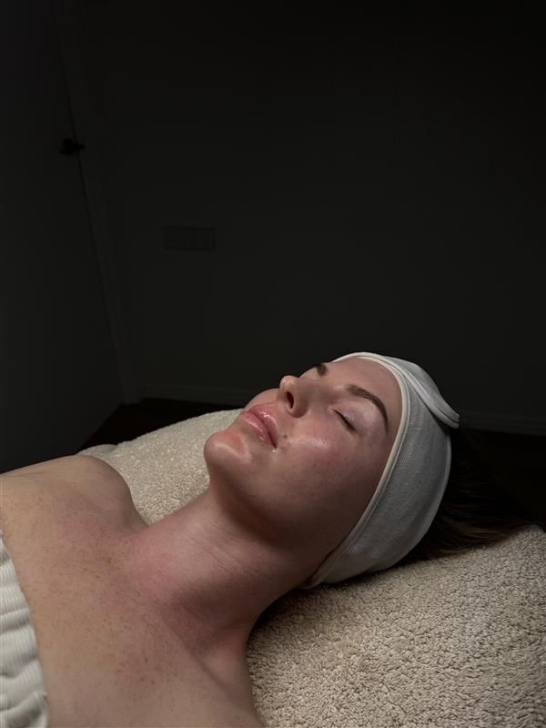 Woman with head wrap, eyes closed, laying on a spa bed; skin treatment on neck and face.— Bombshell Body Bar In Meikleville Hill, QLD