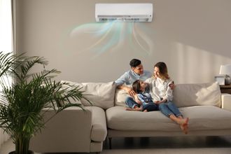 Une famille est assise sur un canapé sous un climatiseur dans un salon.