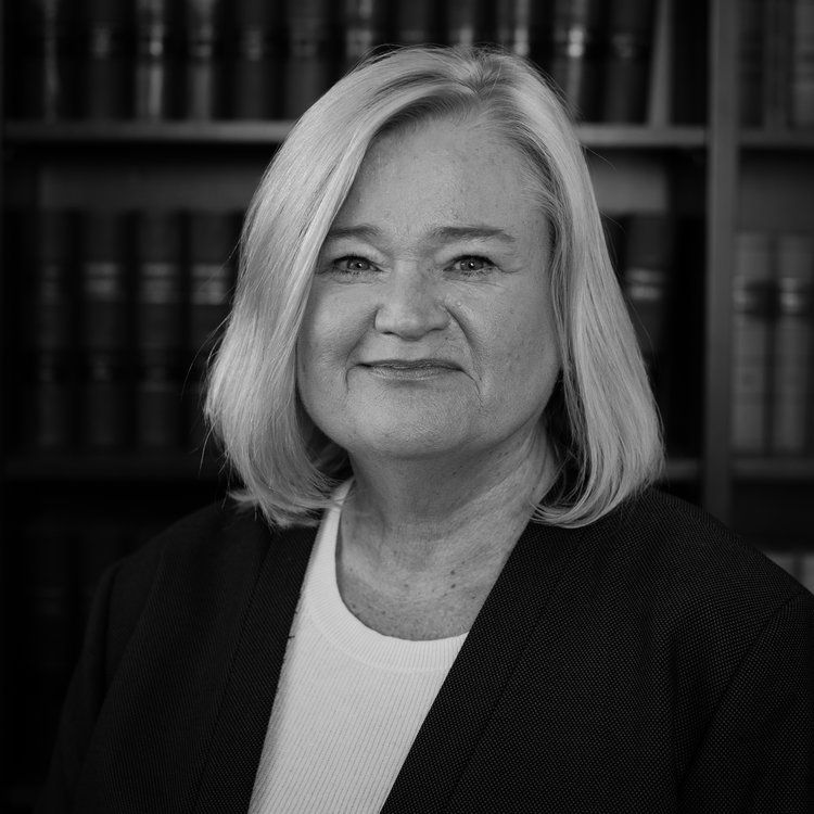 a black and white photo of a woman in front of a bookshelf