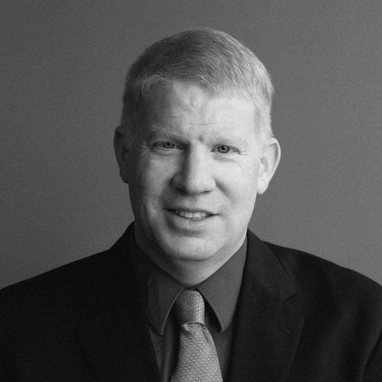 A man in a suit and tie is smiling in a black and white photo.