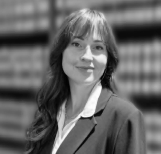 A black and white photo of a woman smiling in front of a bookshelf.