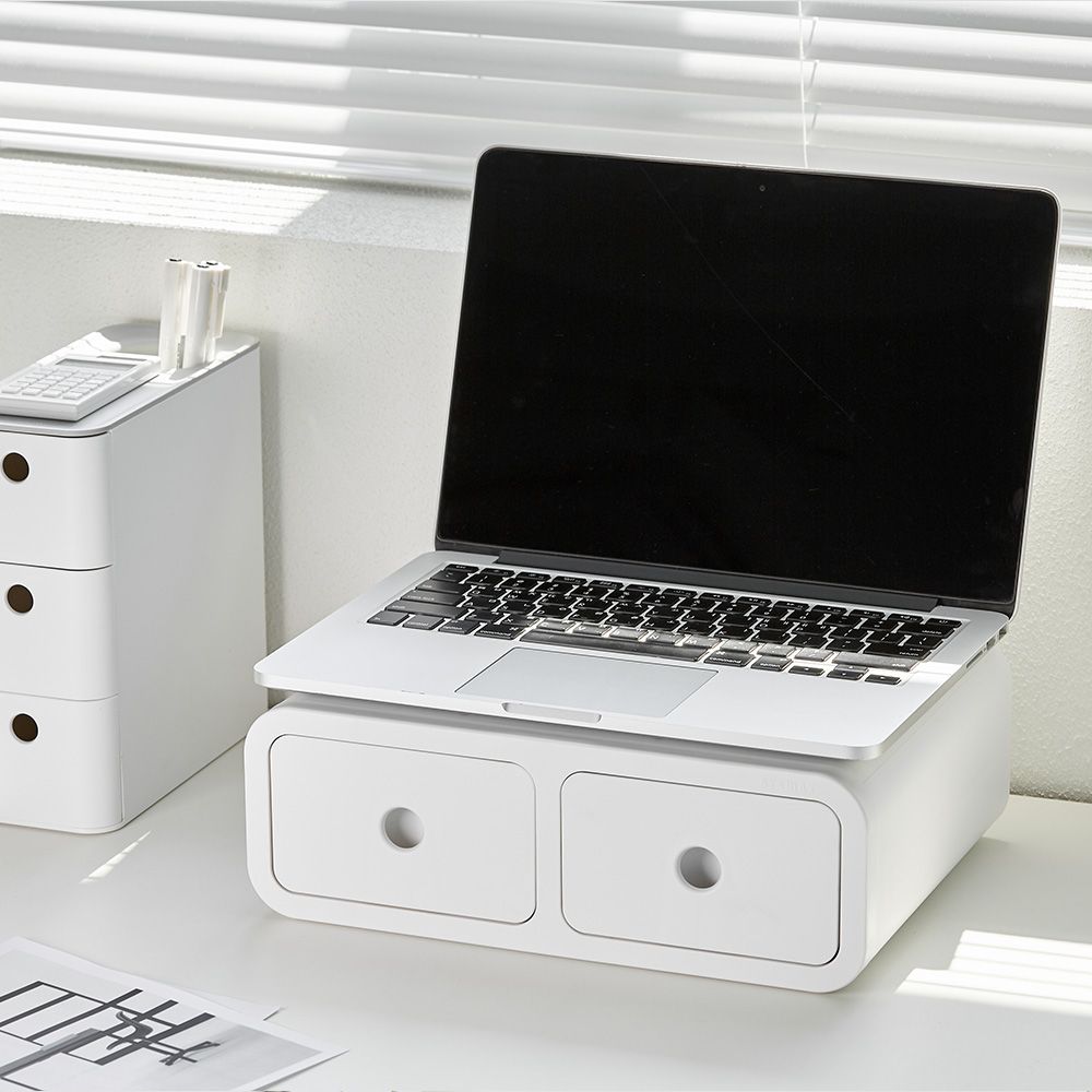 Un ordenador portátil está encima de una caja blanca en una mesa.