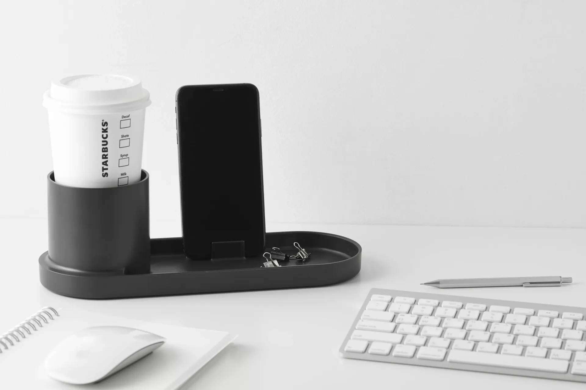 Una taza de café Starbucks está sobre una mesa junto a un teclado y un ratón.