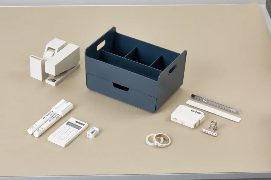 Una mesa con una caja y un montón de material de oficina encima.