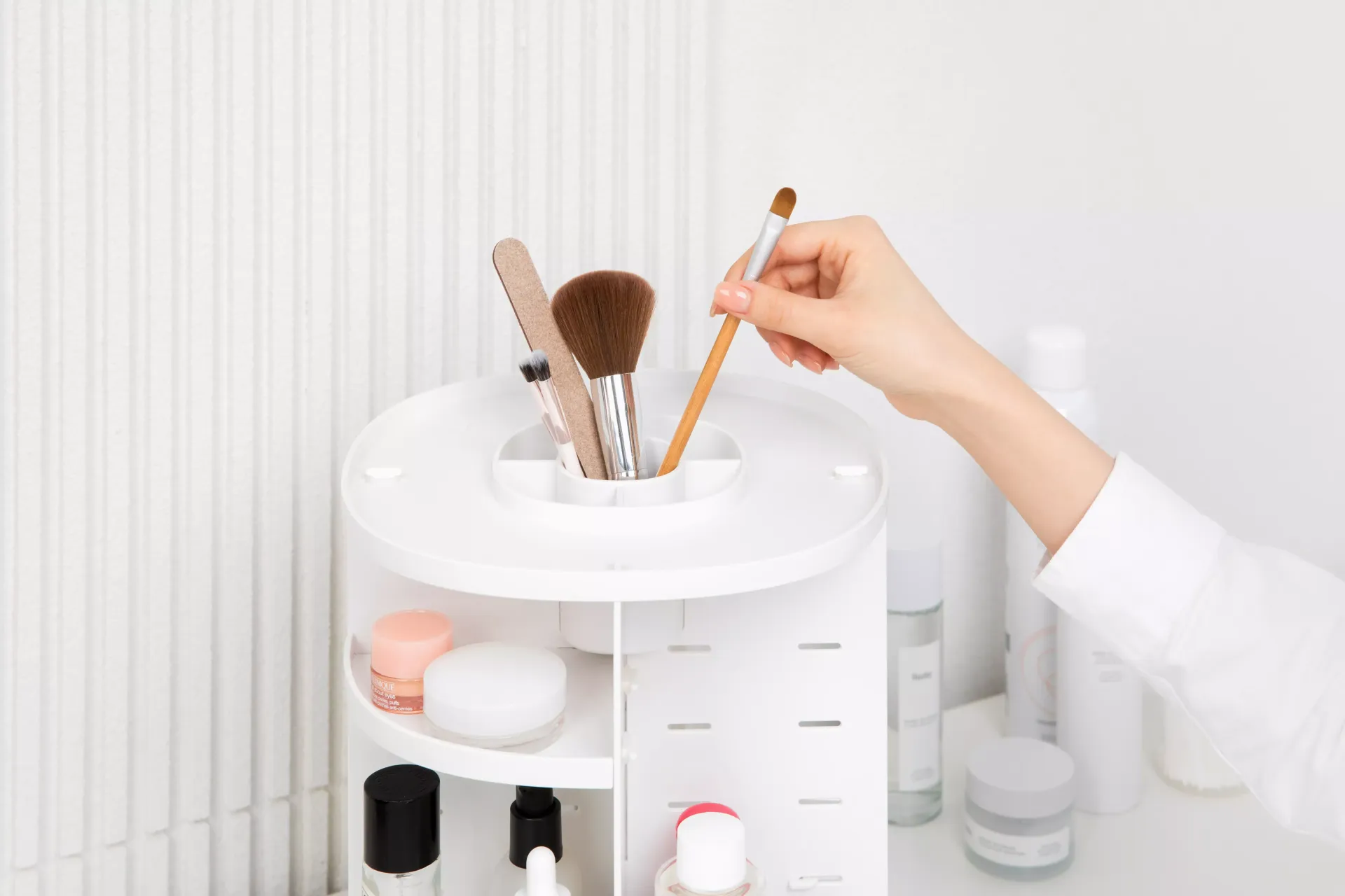 Una persona sostiene un pincel en un organizador de maquillaje.