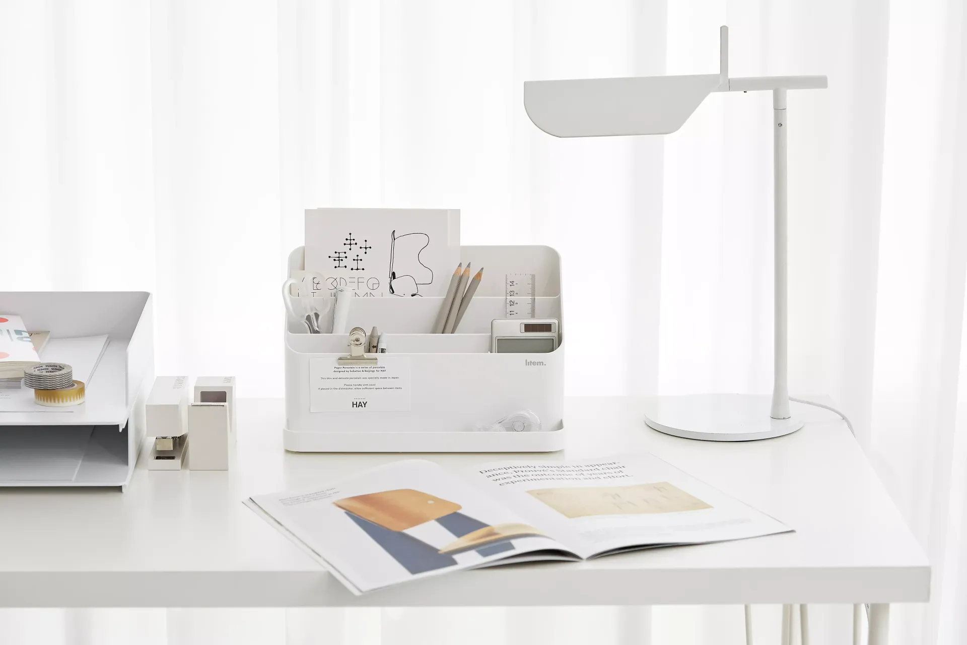 Una mesa blanca con una lámpara y una revista encima.