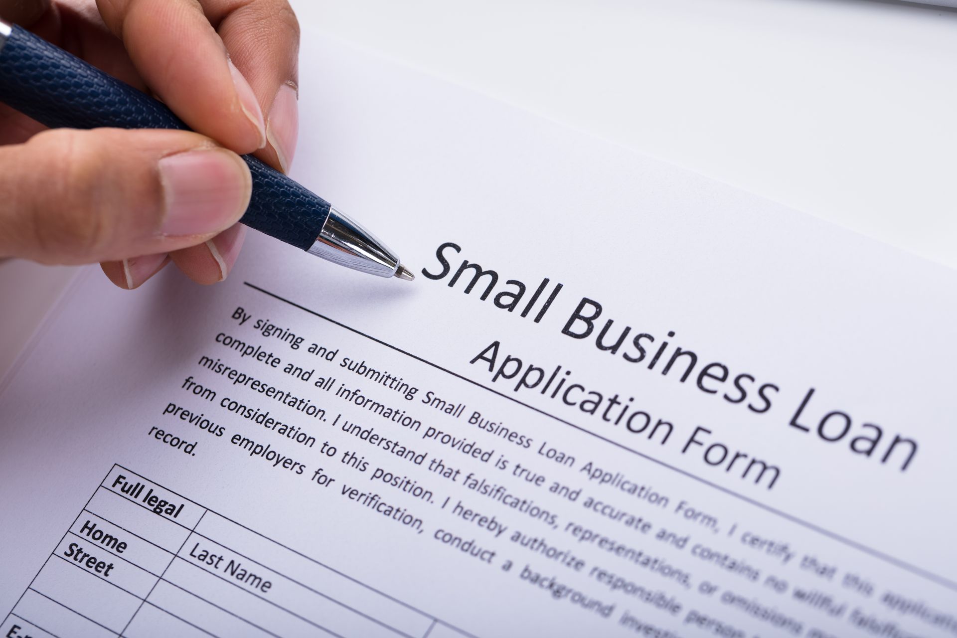 Business owner reviewing and completing a loan application form. Business owner reviewing and completing a loan application form.