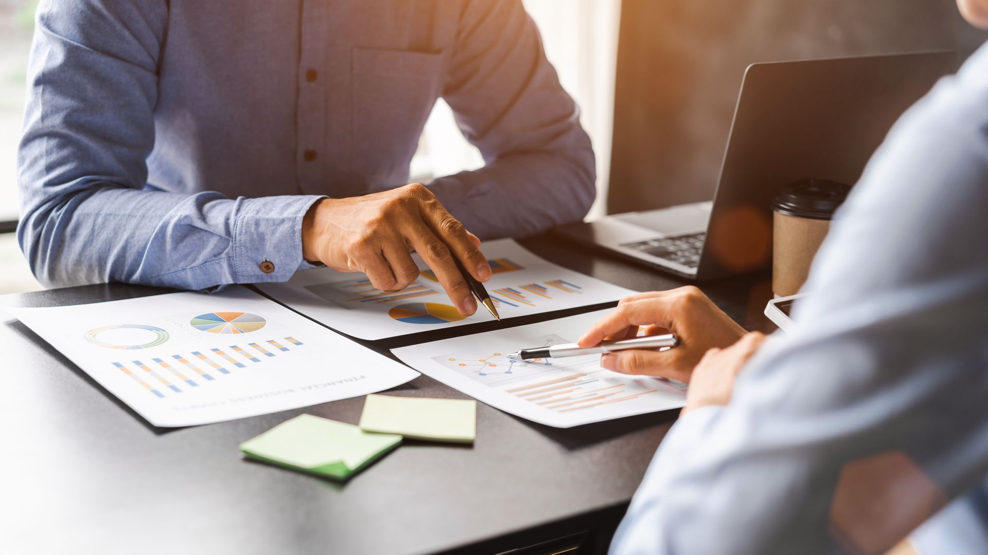 An accountant and a client reviewing financial charts and reports during a meeting.