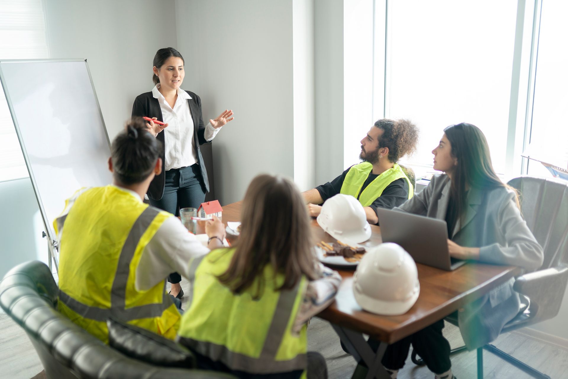 A finance expert is talking about a project in the meeting room with her team sitting around a table