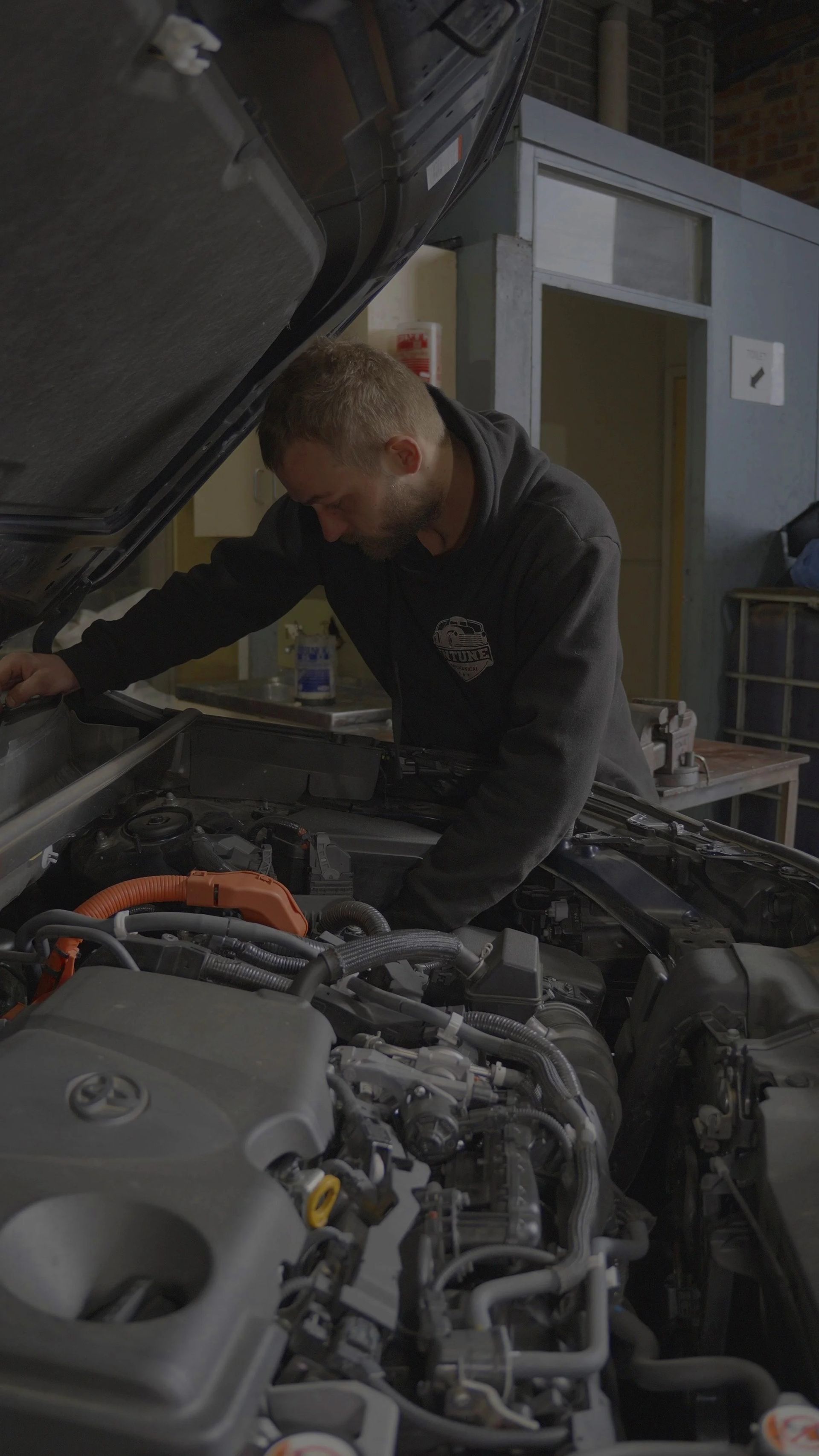 Mechanic inspecting a car engine in a garage with the hood raised