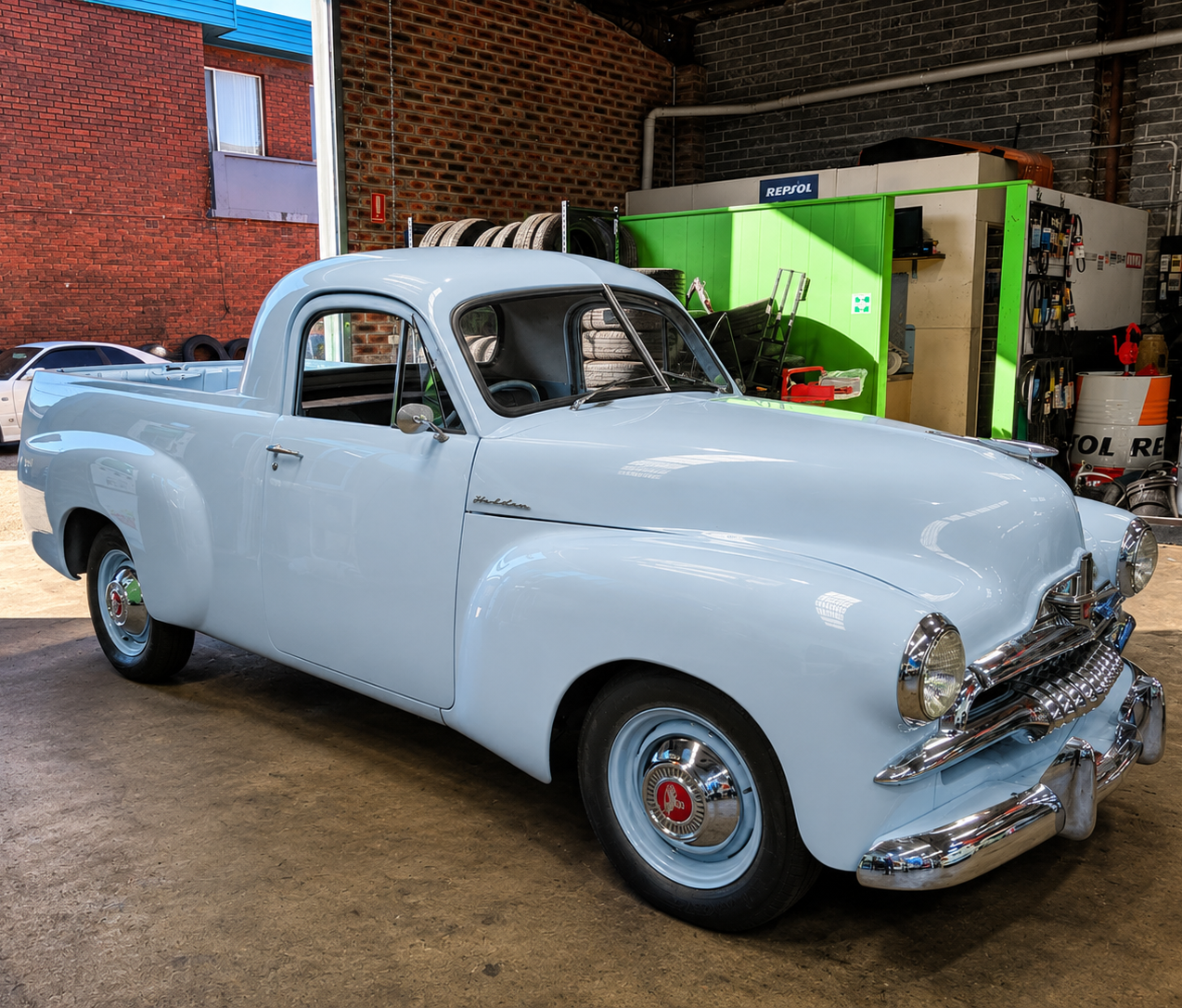Classic white vintage pickup truck parked indoors in a garage or showroom.