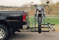 A motorcycle is attached to the back of a truck.