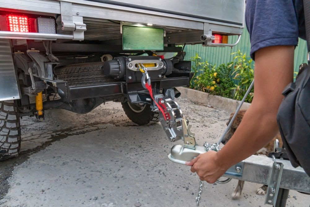 A man is attaching a trailer to a truck.