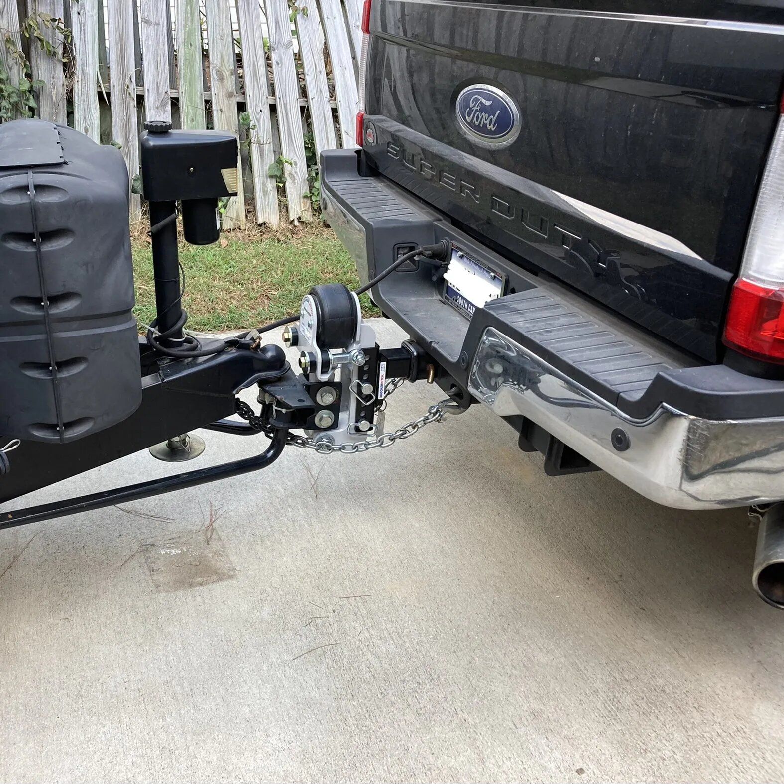 A black ford truck is towing a trailer.