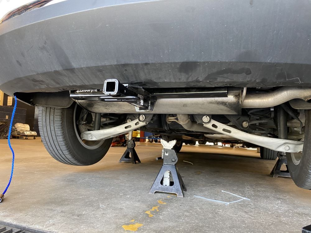 A car is sitting on a jack in a garage.