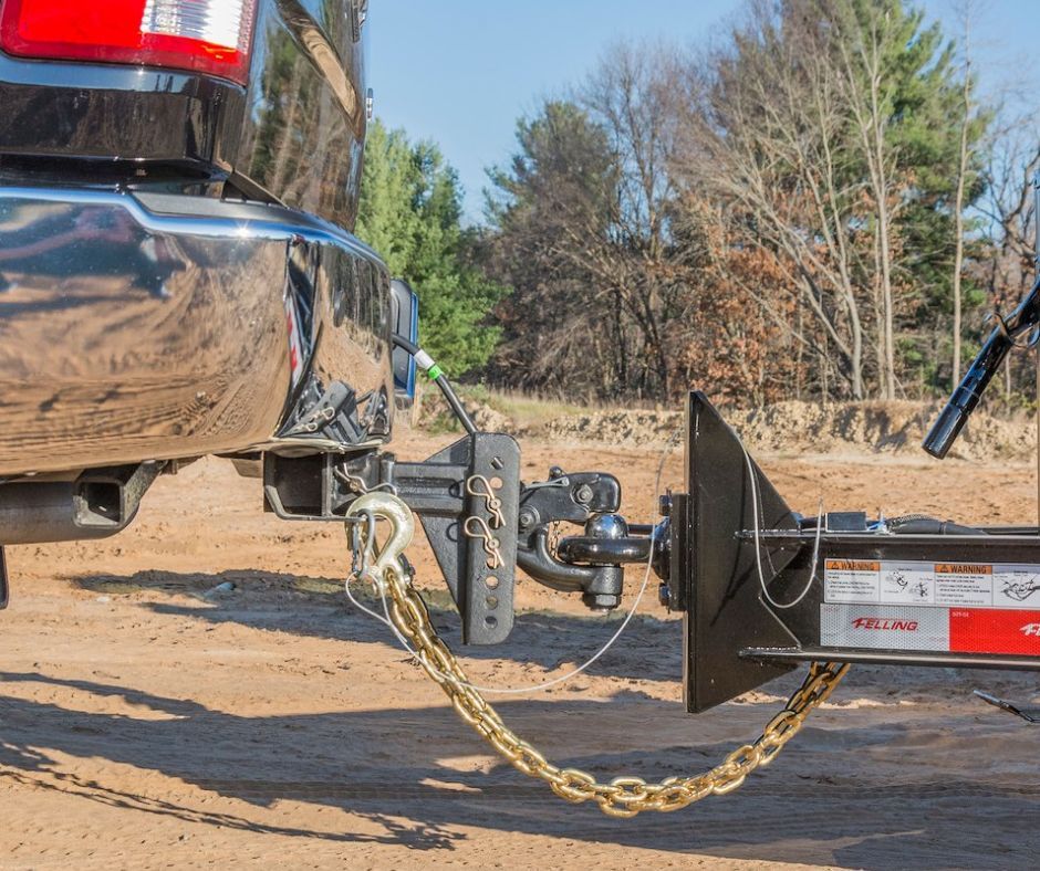 A truck is towing a trailer on a dirt road.