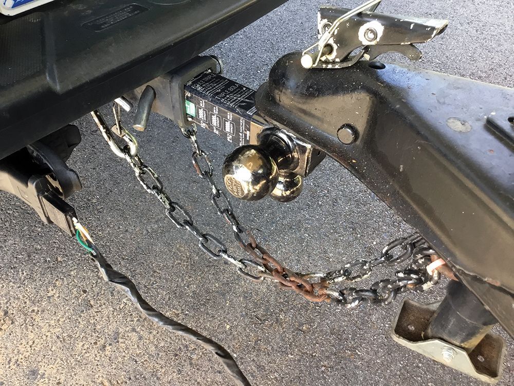 A close up of a trailer hitch with a chain attached to it.