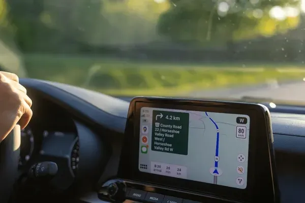 A person is driving a car with a navigation system on the dashboard.