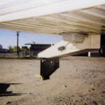 A person is standing under a bridge in a parking lot.