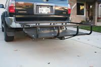 A car with a cargo rack attached to the back of it is parked in a driveway.