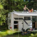 A woman is sitting on the roof of a rv.