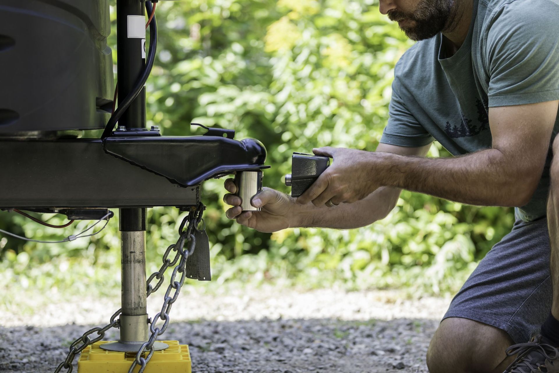 A man is kneeling down to fix a trailer.