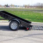 A black trailer is parked on the side of the road.