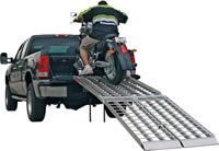 A man is loading a motorcycle into the back of a truck.