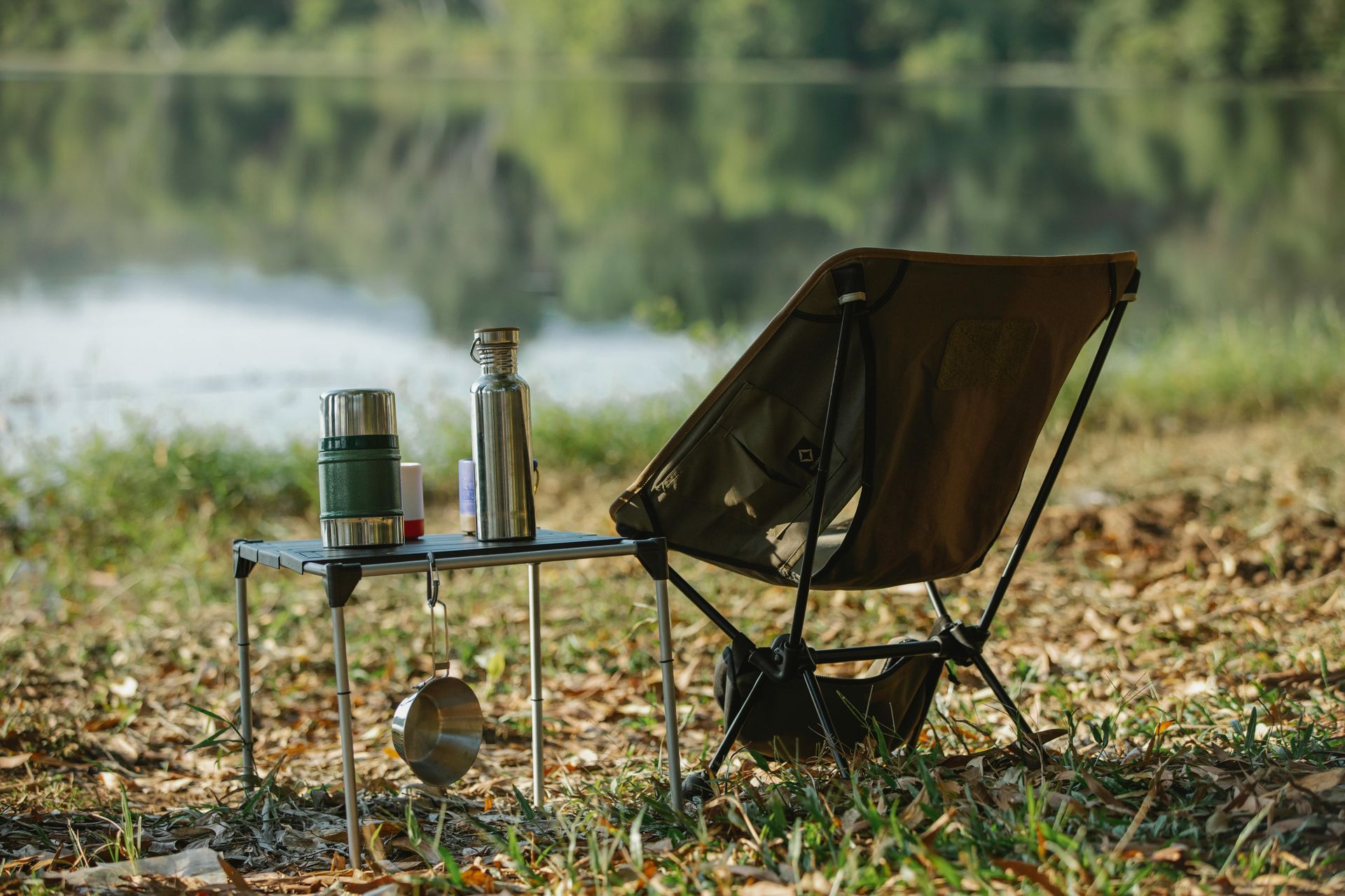 A chair is sitting on top of a small table next to a lake.