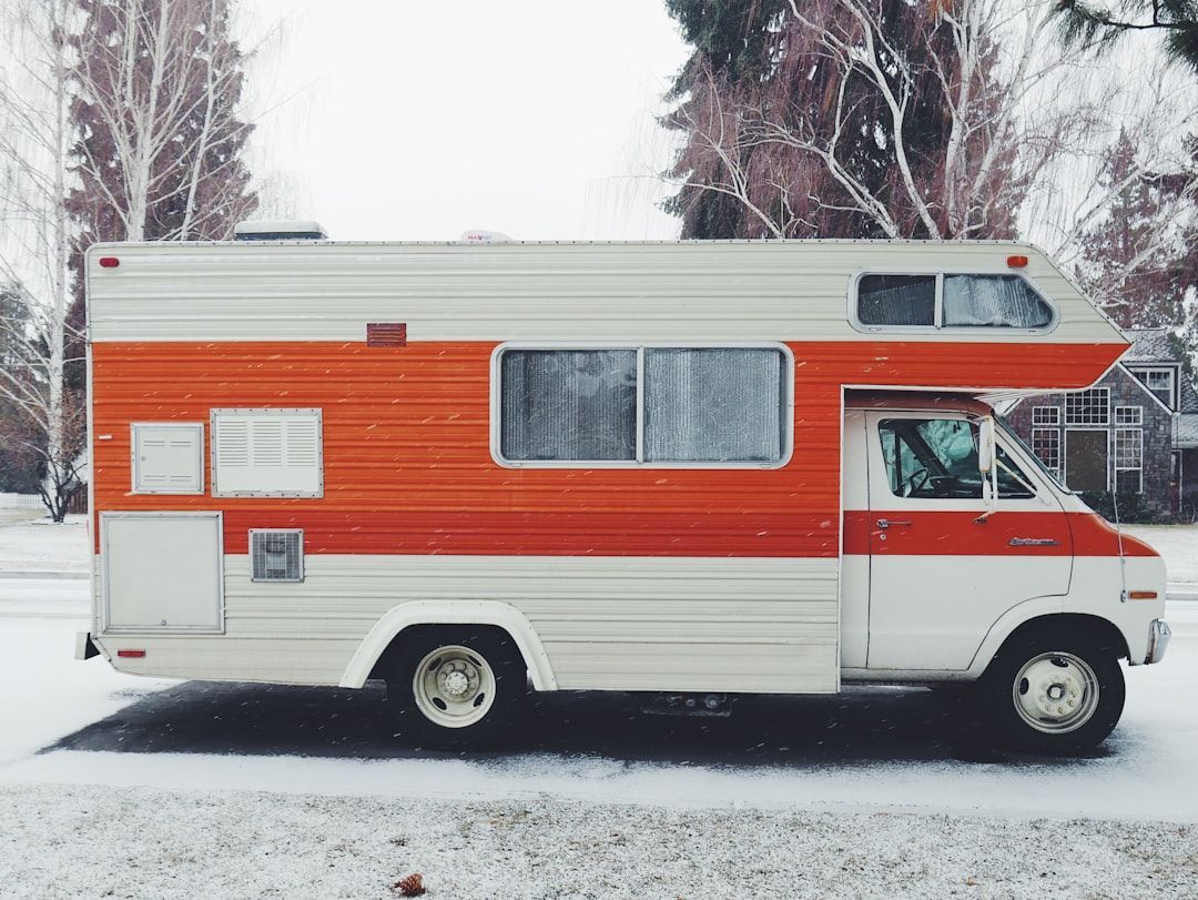 A red and white rv is parked in the snow.