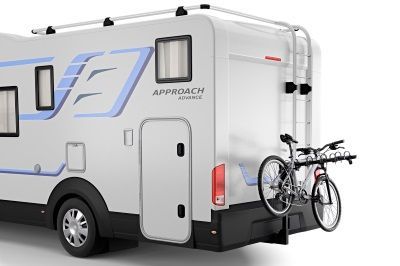 A white rv with a bicycle attached to the back of it.