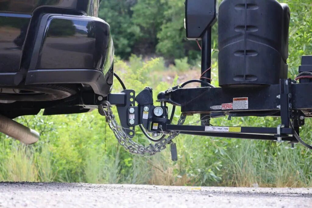 A truck is towing a trailer down a dirt road.