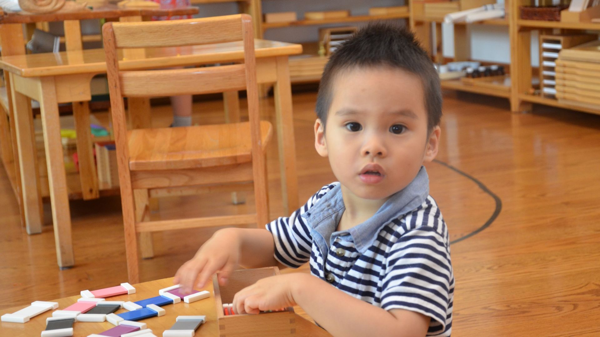 A Montessori child is sitting at a table working with materials.
