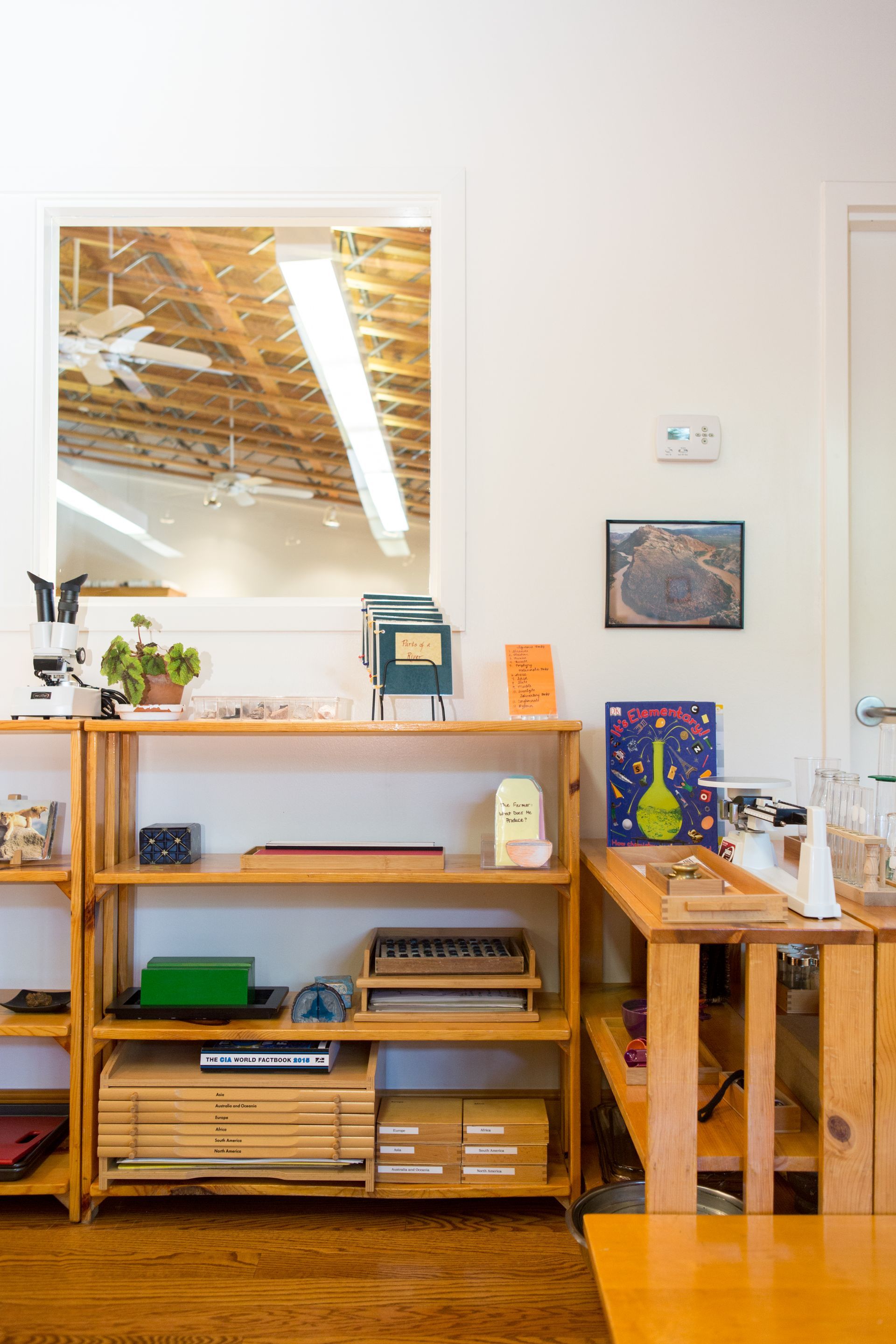 A Montessori room with wooden shelves, a table, and a window.