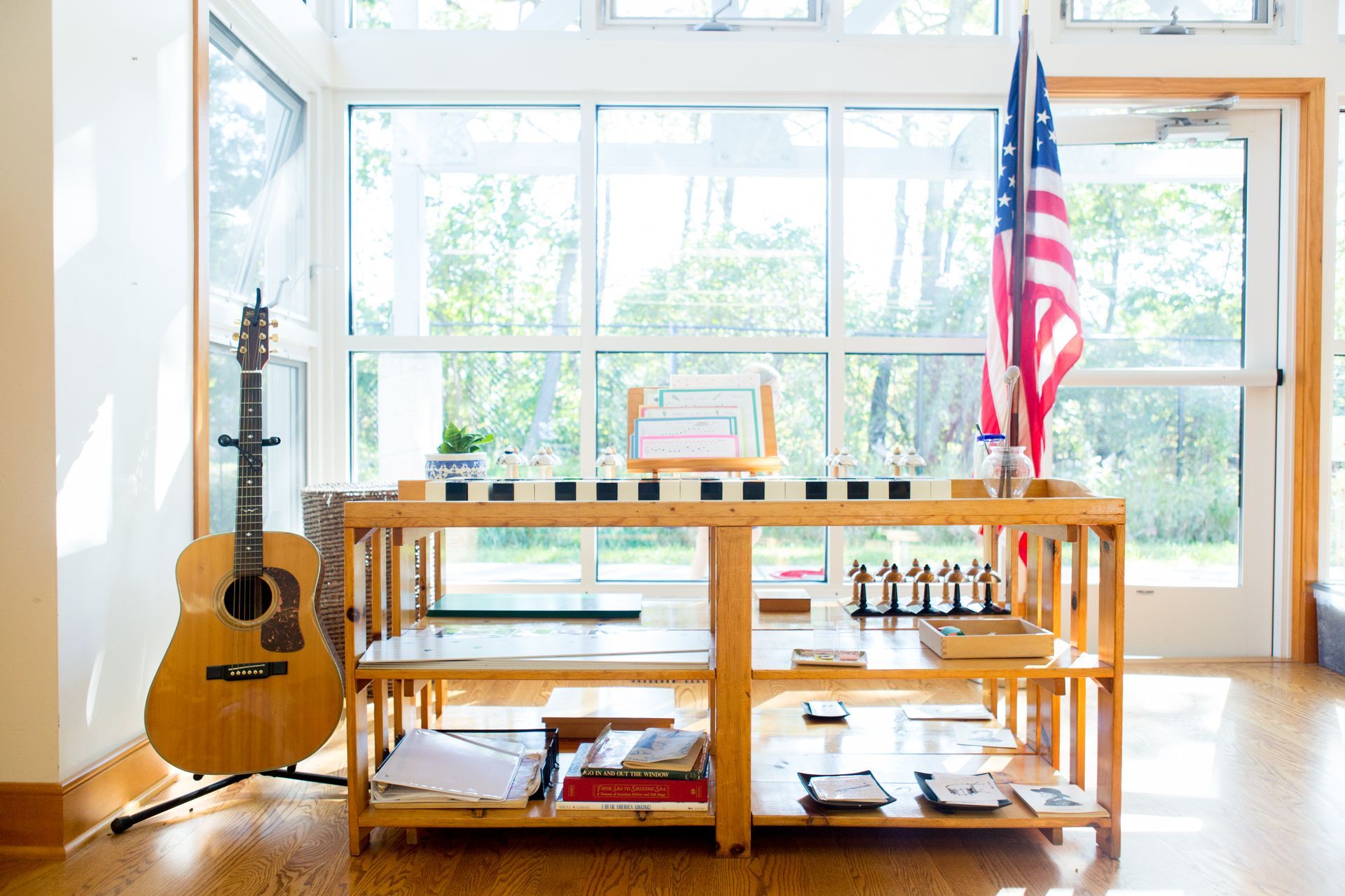 A guitar is sitting on top of a wooden shelf next to an american flag.