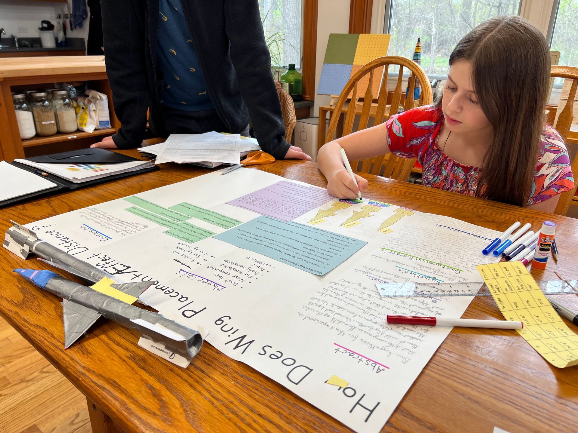 A Montessori child is sitting at a table writing on a piece of paper.